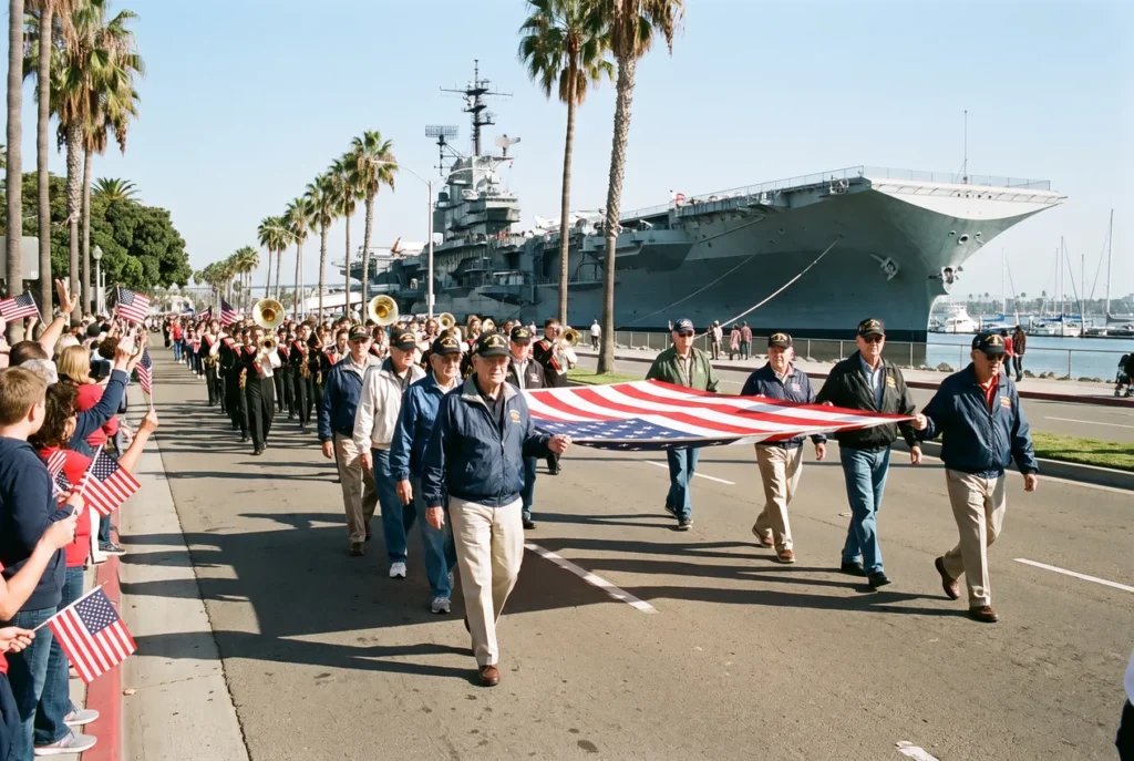 Spectators with small American flags lining Harbor Drive in San Diego on a clear November morning as a parade of veterans passes, the USS Midway and harbour water behind them